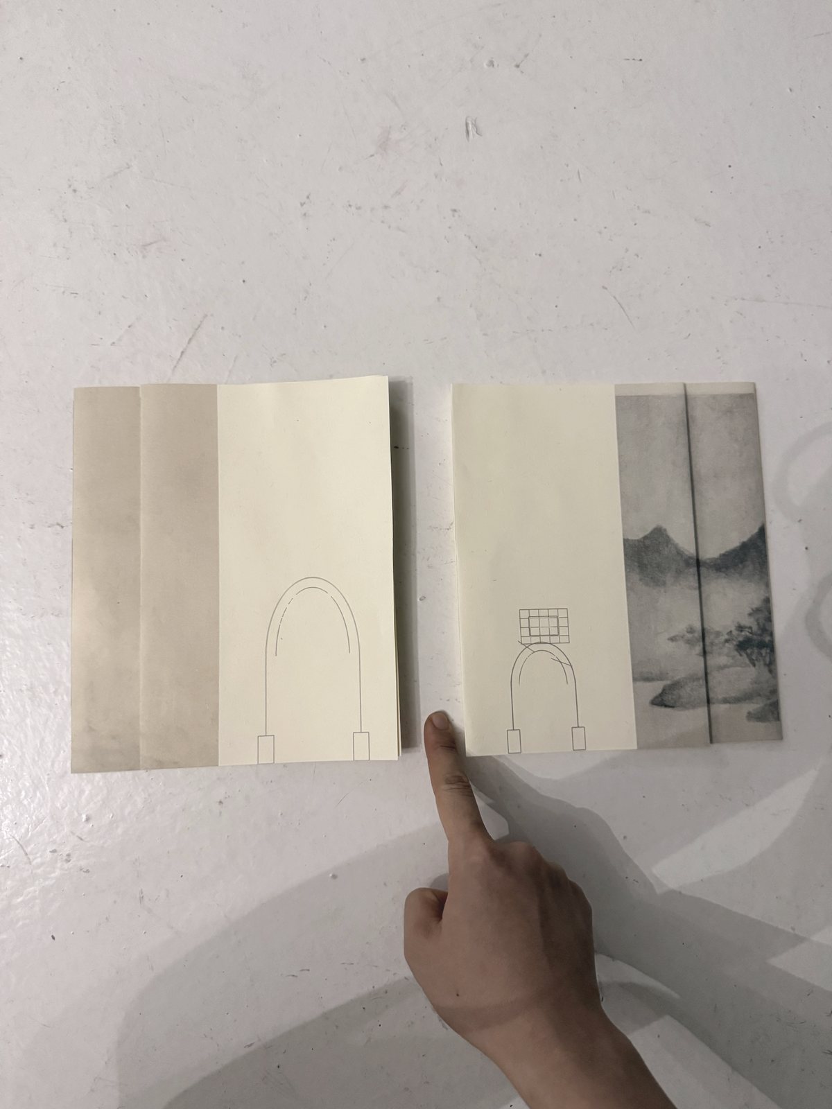 Hand comparing folded paper models for scale, interval and reading direction.