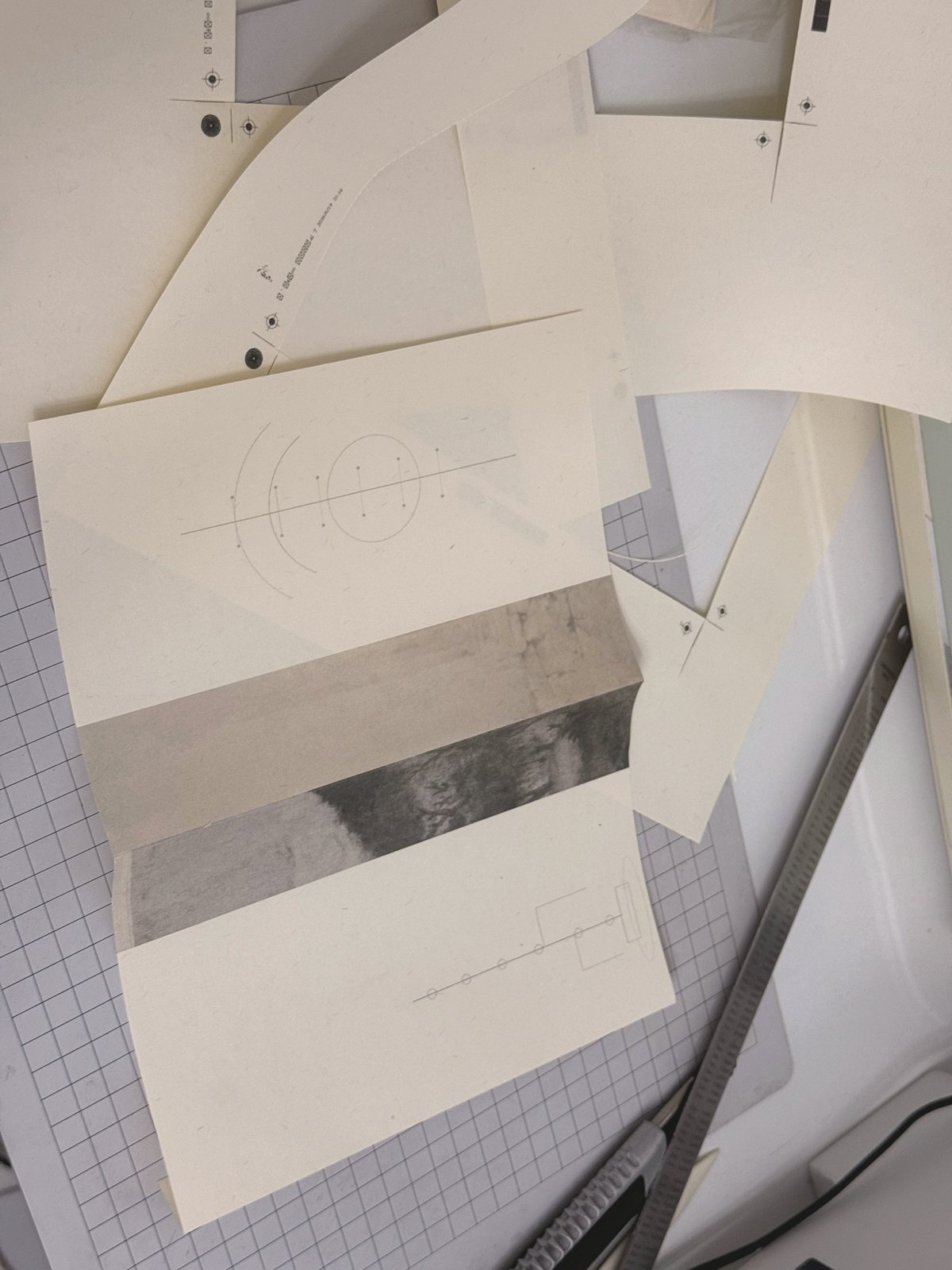 Printed fragments, structural diagrams, ruler and cutting knife on a work table.