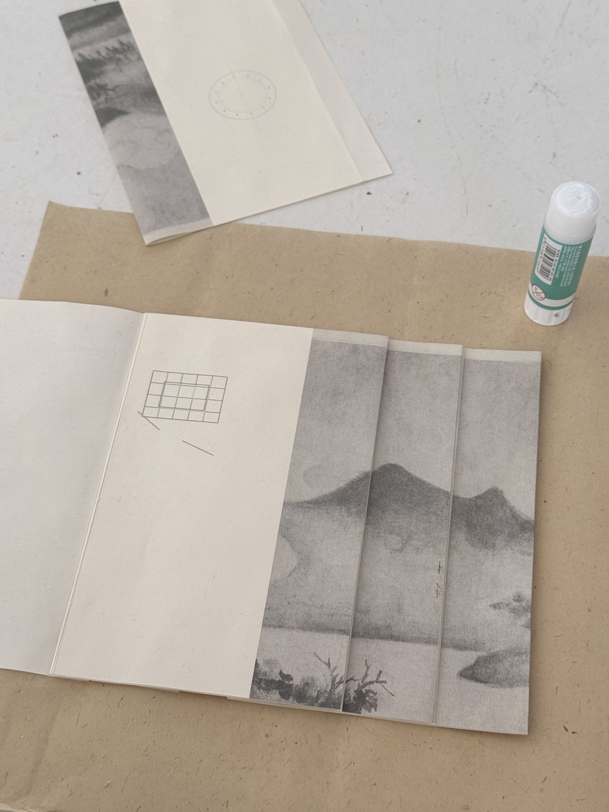 Printed mountain image divided across overlapping paper leaves during assembly.