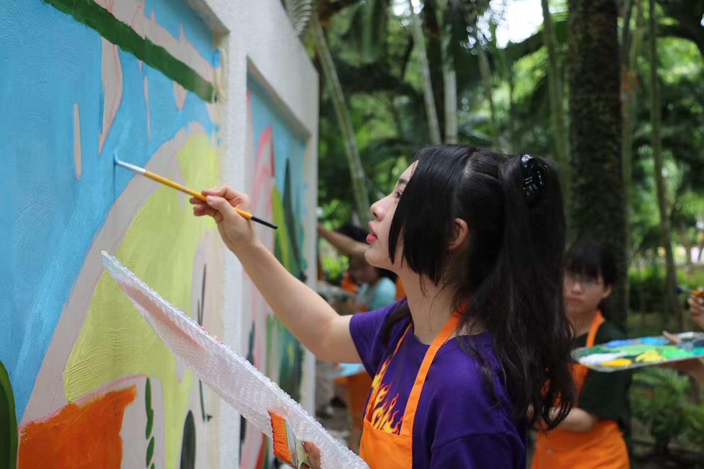 Mengruo Wang painting a mural panel on site