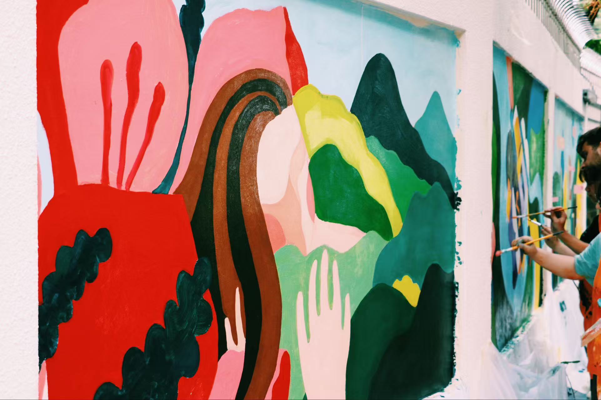 Colourful mural panels being painted along an exterior wall